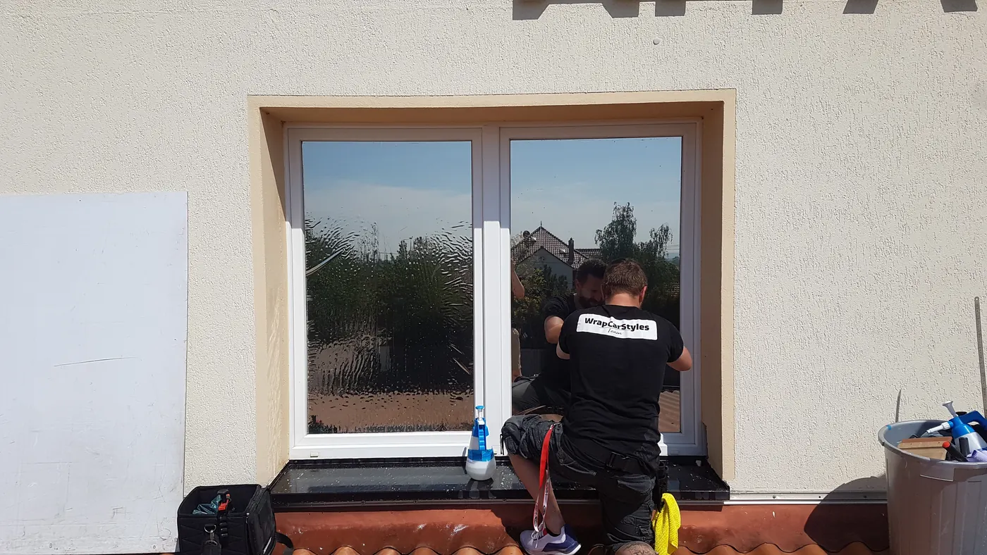 Sandro Messerschmidt von WCS Sonnenschutz bei der Folienmontage an einem Fenster